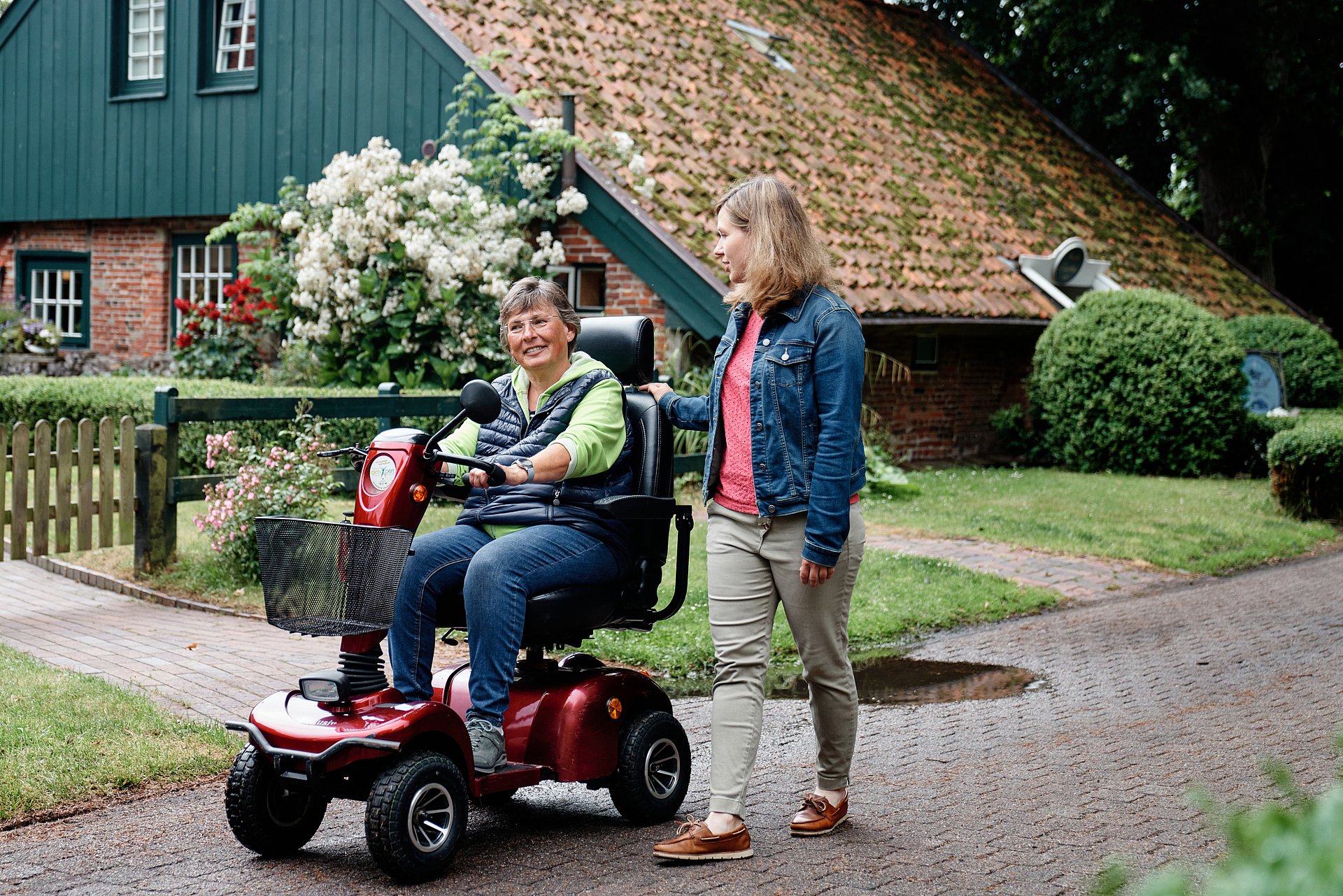 Eine Frau auf einem Scooter wird von einer anderen Frau begleitet.