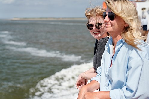 Zwei Frauen stehen an der Rehling und blicken aufs Meer.