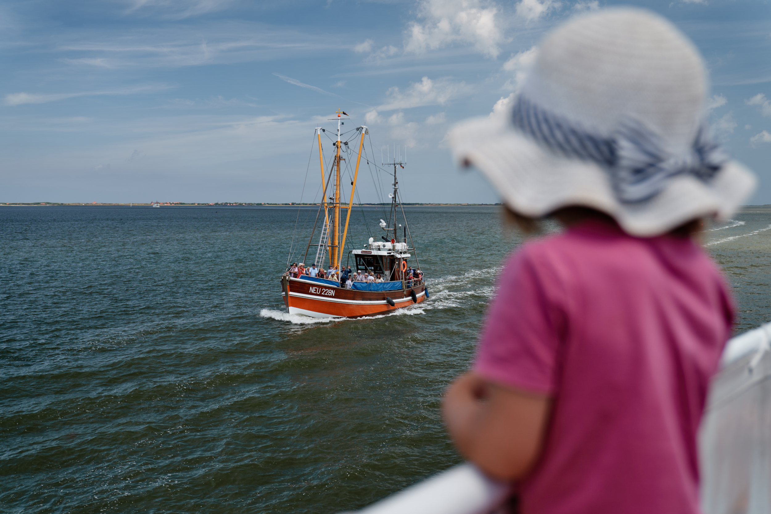 Ein Kind blickt vom Schiff aus auf einen vorbeifahrenden Fischkutter