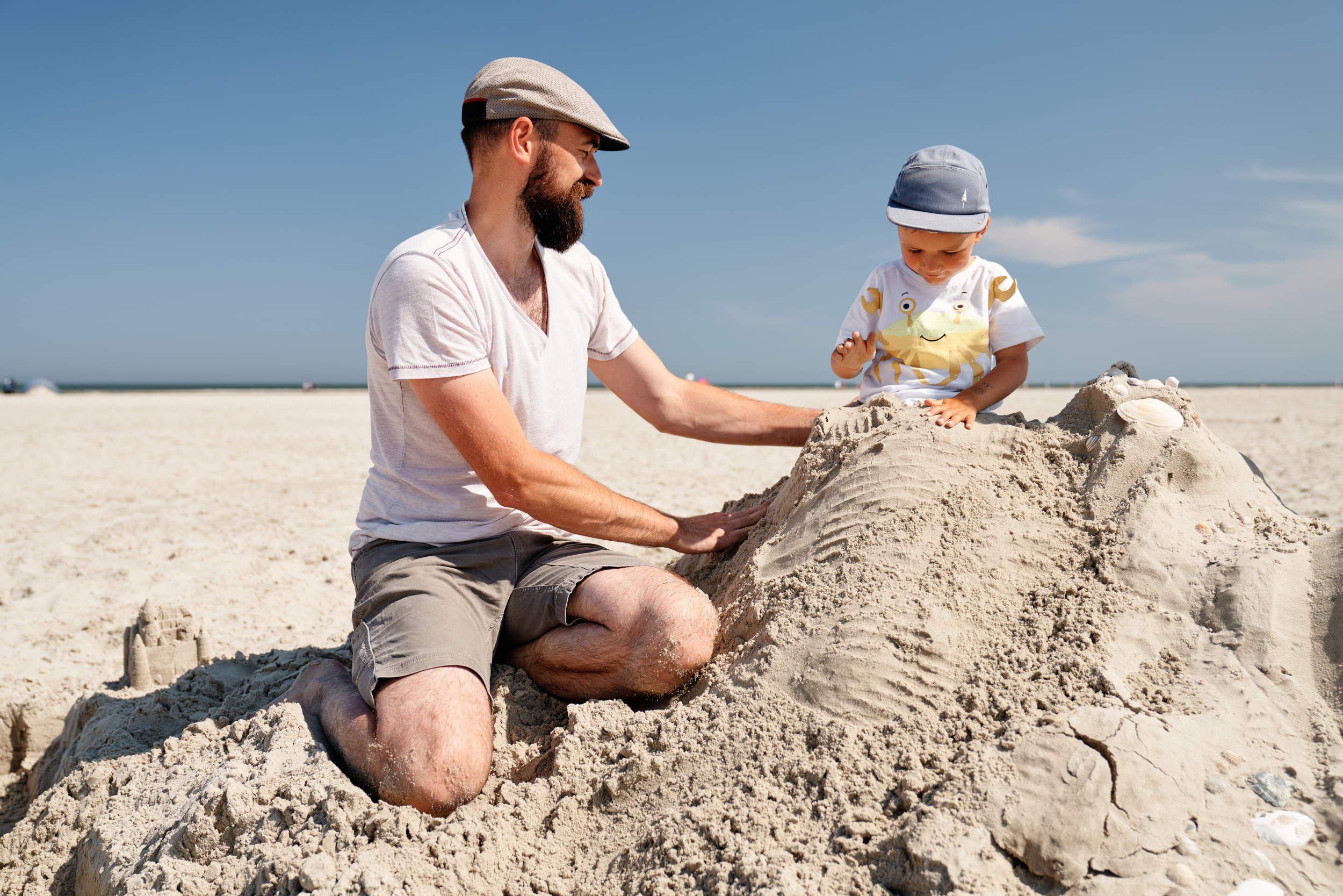Ein Vater baut mit seinem Kind eine Sandburg
