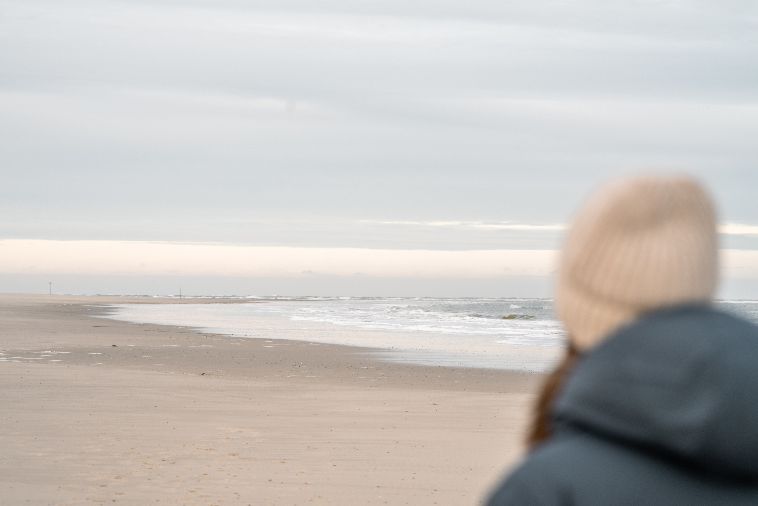 Eine Frau bei einem Spaziergang am Spiekerooger Strand