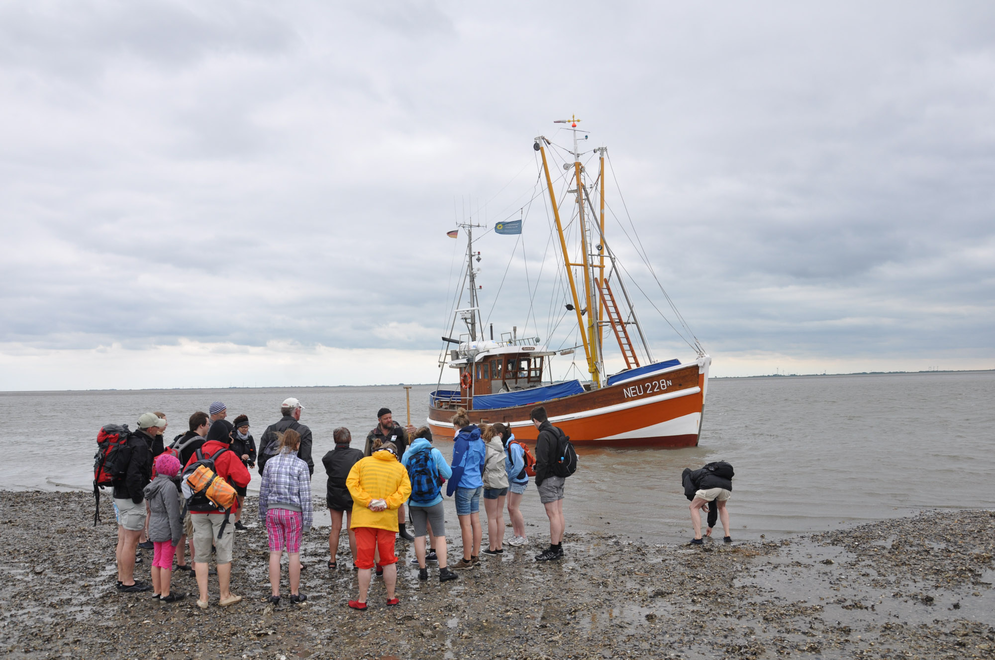 Eine Gruppe von WattwanderInnen steht vor einem Fischerboot