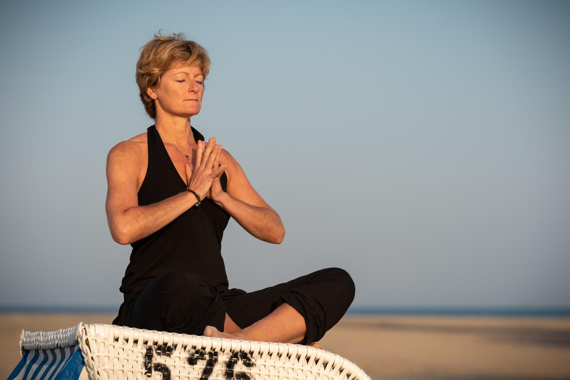 Indra Dijkgraaf sitzt in Yoga Pose auf einem Strandkorb am Strand von Spiekeroog.