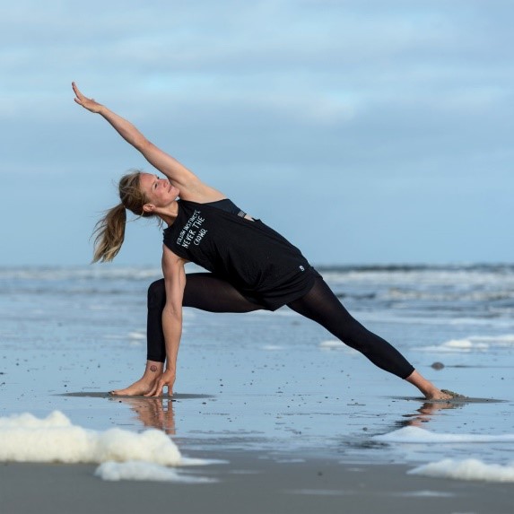 Maxie Neubacher steht in Yoga Pose am Spülsaum am Strand von Spiekeroog.