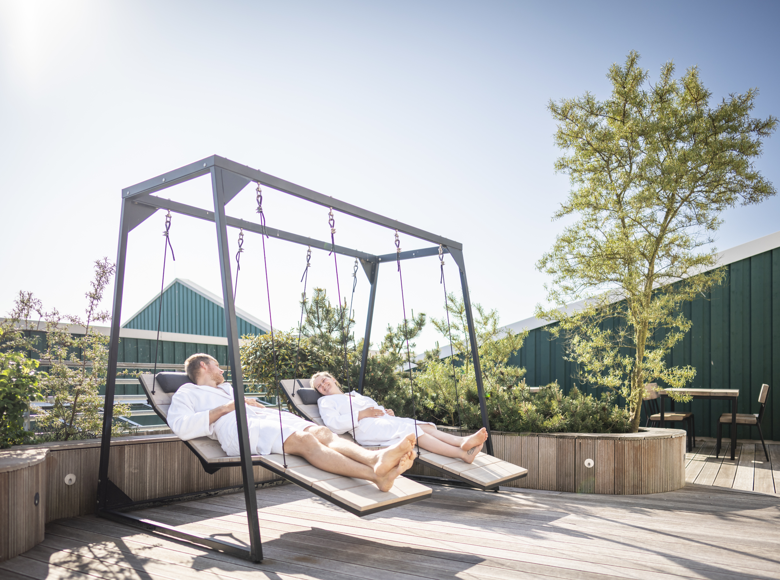 Gäste liegen auf den Ruheschaukeln auf der Terrasse des DünenSpa im Meerestied auf Spiekeroog.