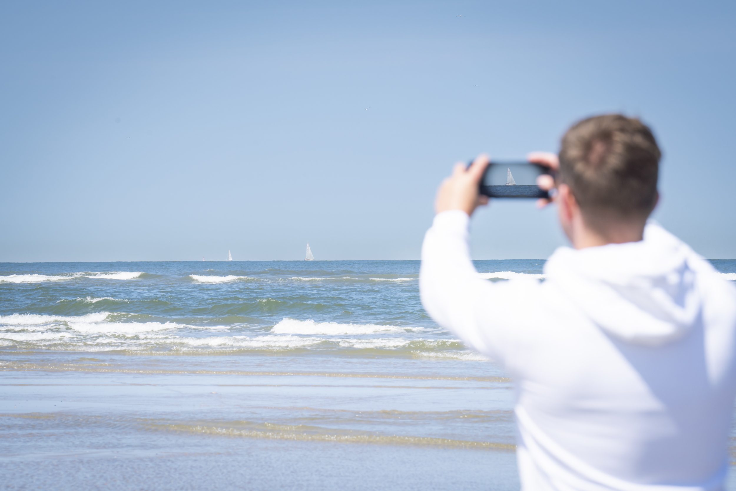 Ein Mann macht mit dem Handy ein Bild vom Meer auf Spiekeroog 