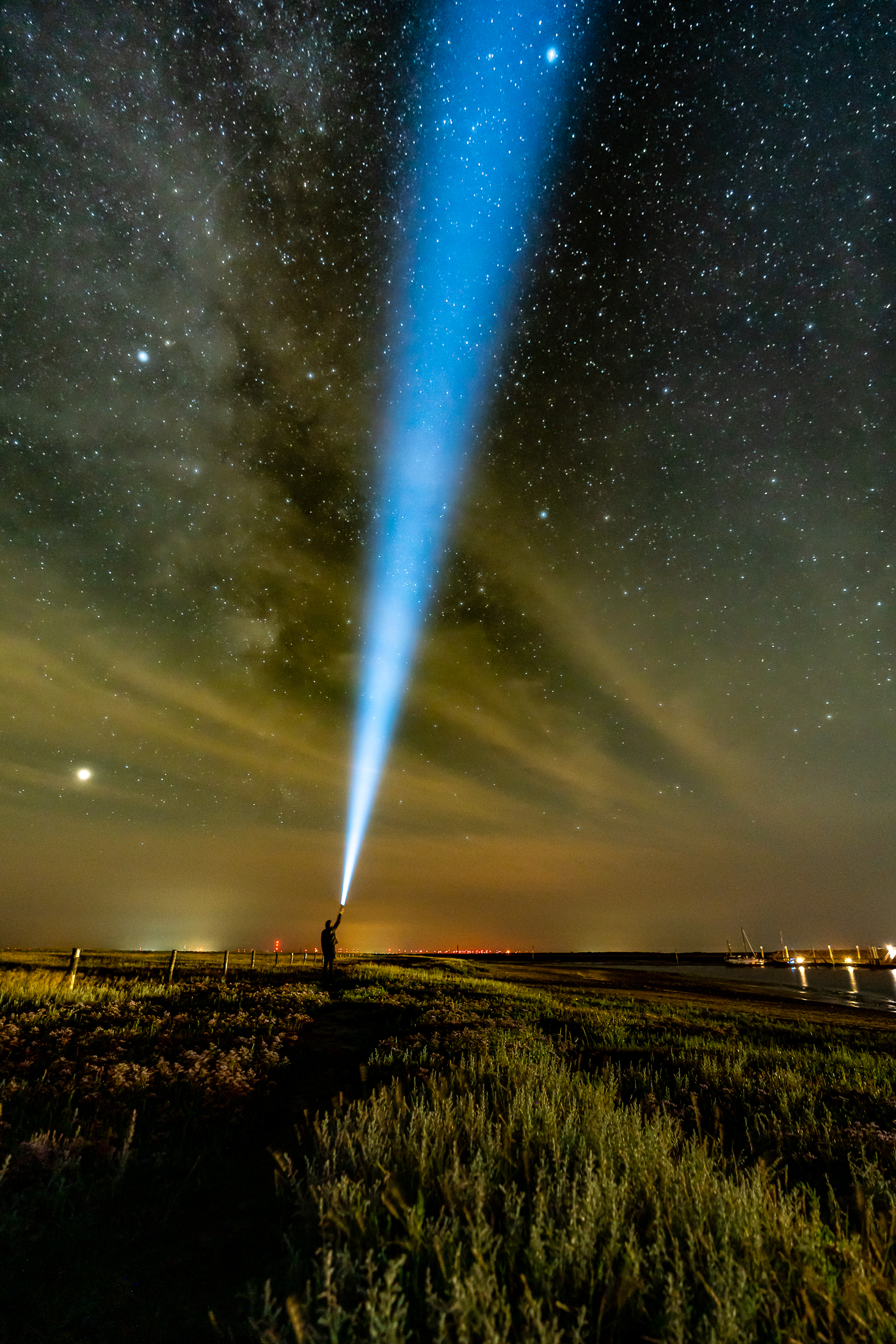 Ein Mensch leuchtet mit einer Taschenlampe in den Spiekerooger Nachthimmel