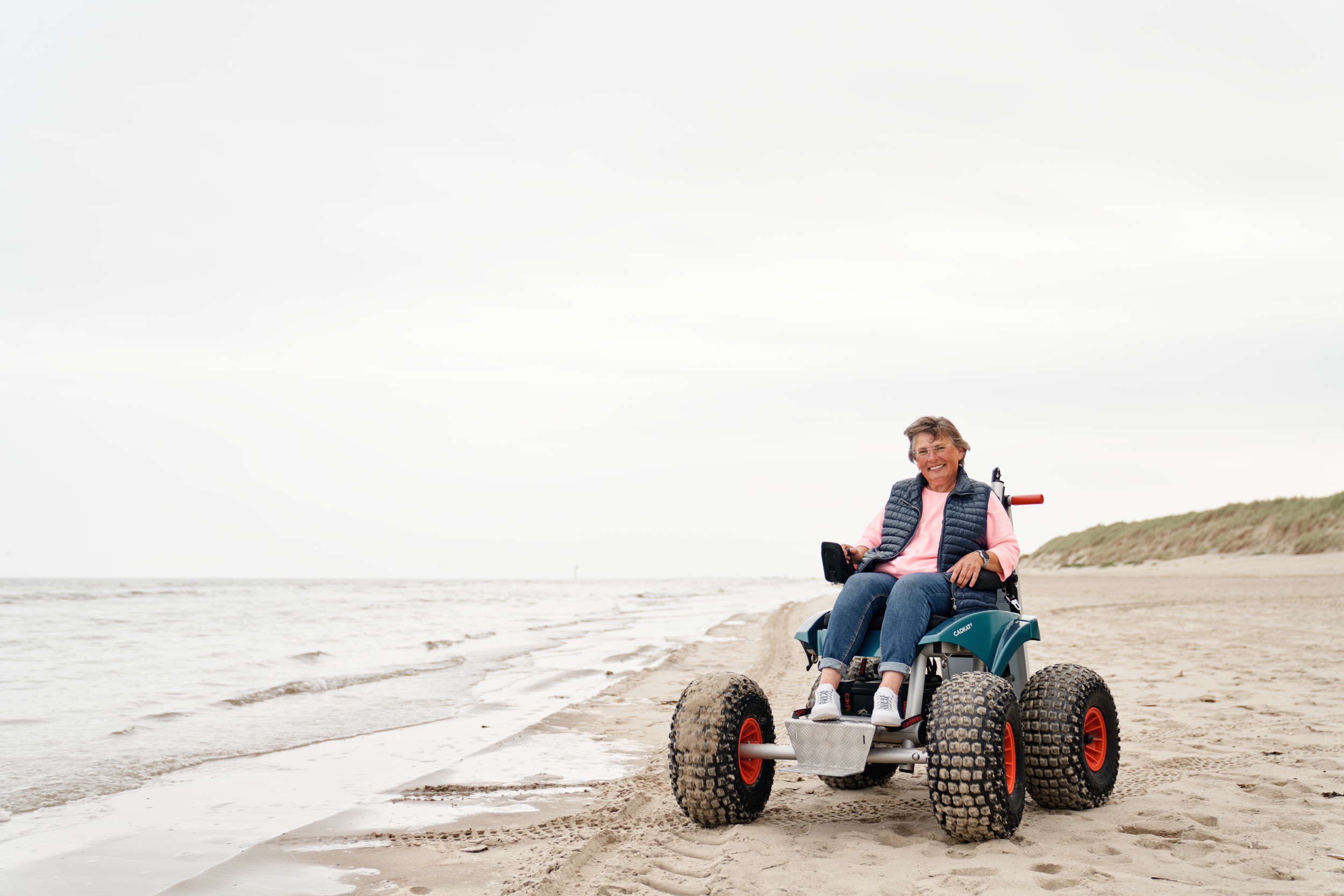 Eine Frau mit Strandmobil an der Wasserkante am Spiekerooger Strand