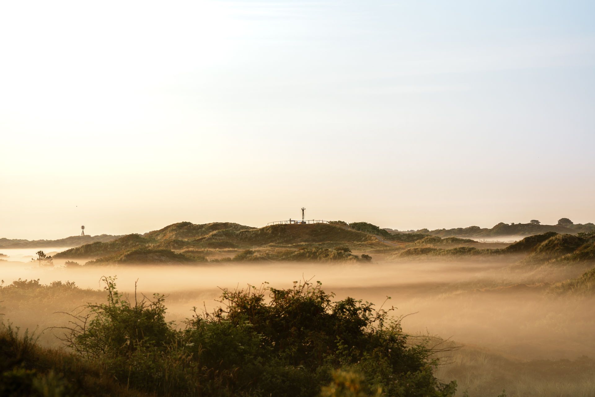 Blick von einer Düne Richtung Osten auf den Utkieker über dunstige Dünentäler auf Spiekeroog im Querformat