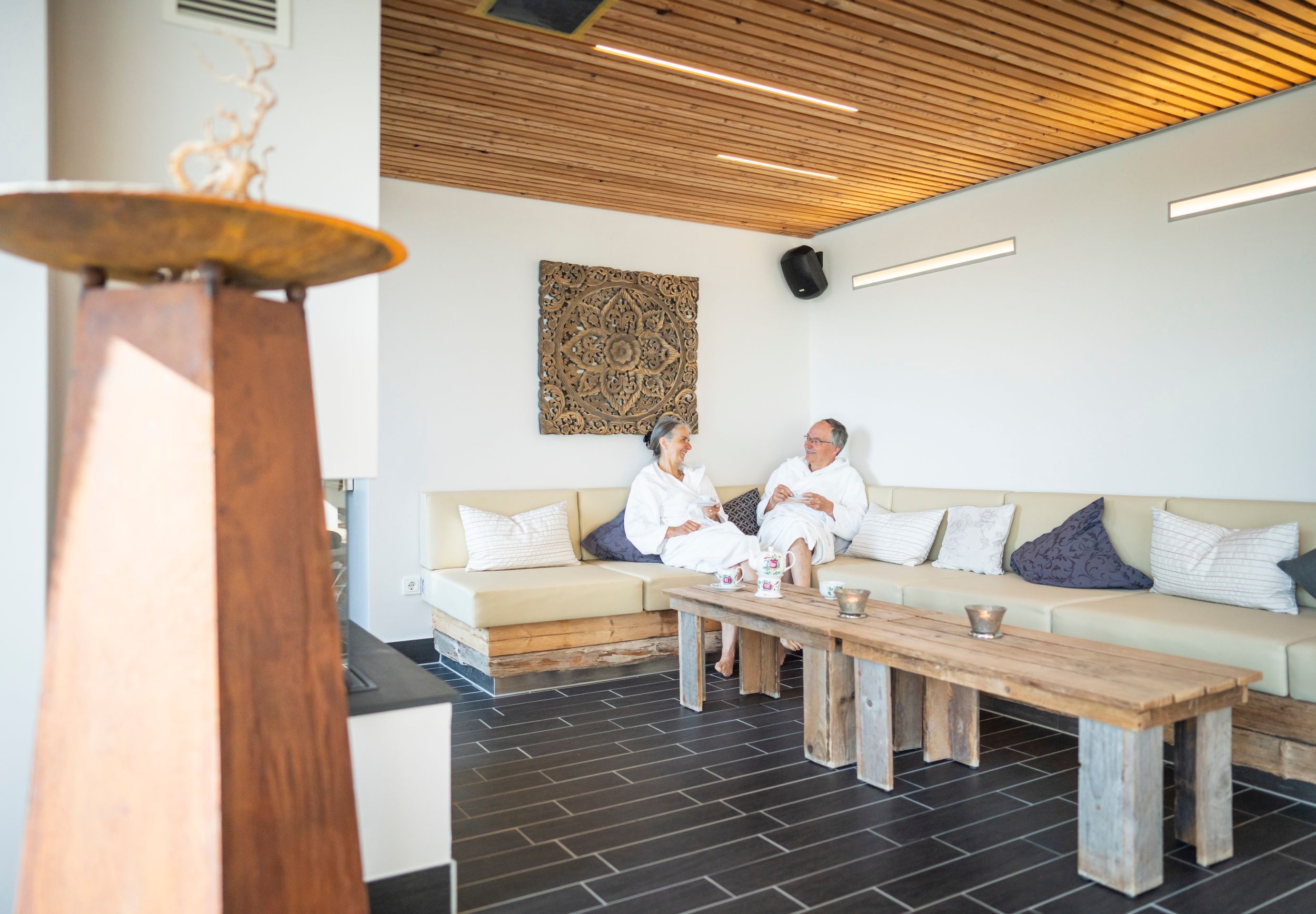 Ein älteres Paar sitzt in der Kaminlounge des DünenSpa im Meerestied auf Spiekeroog.