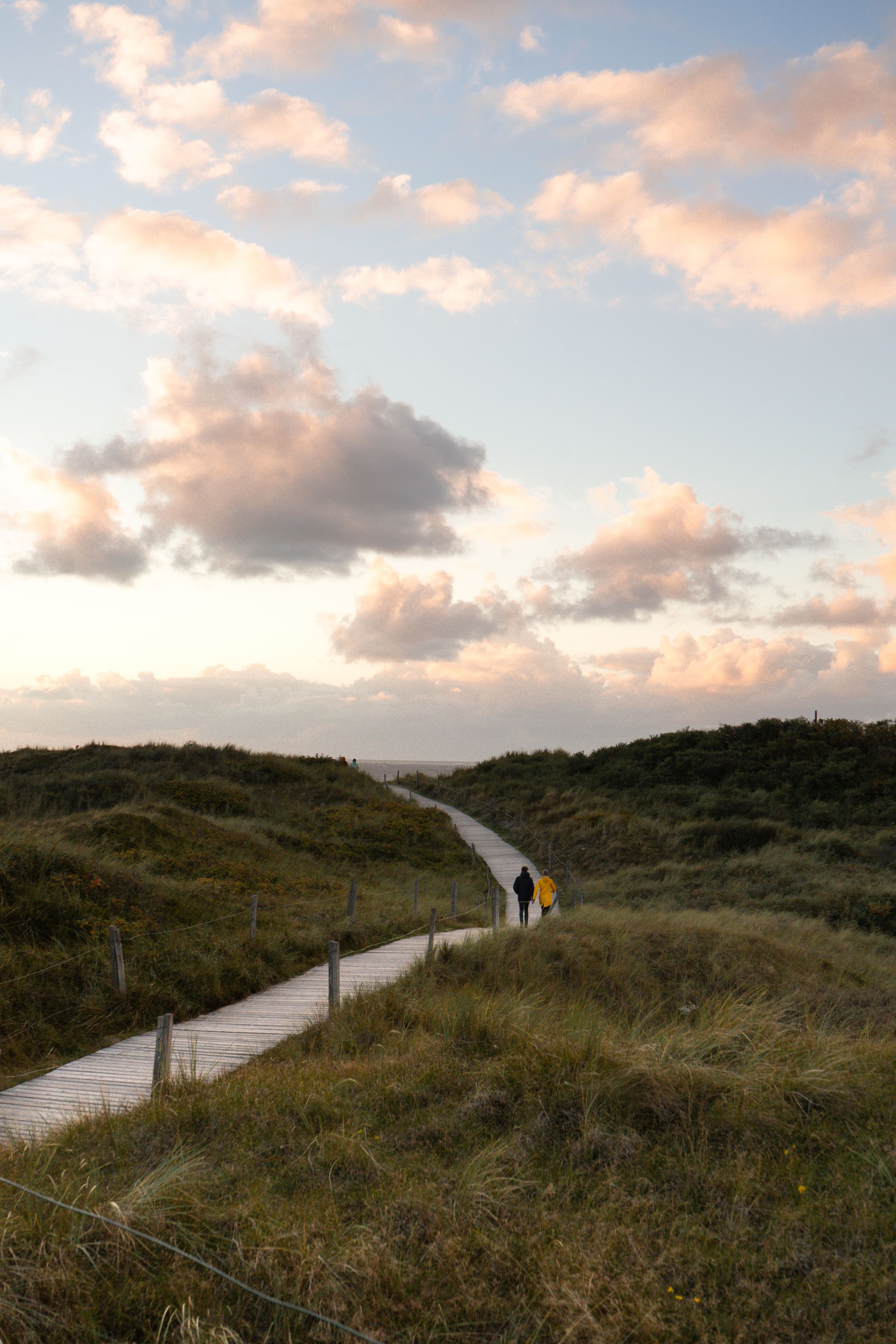 Zwei Menschen auf dem Bohlenweg am Strandabgang evangelischer Jugendhof in Richtung Strand